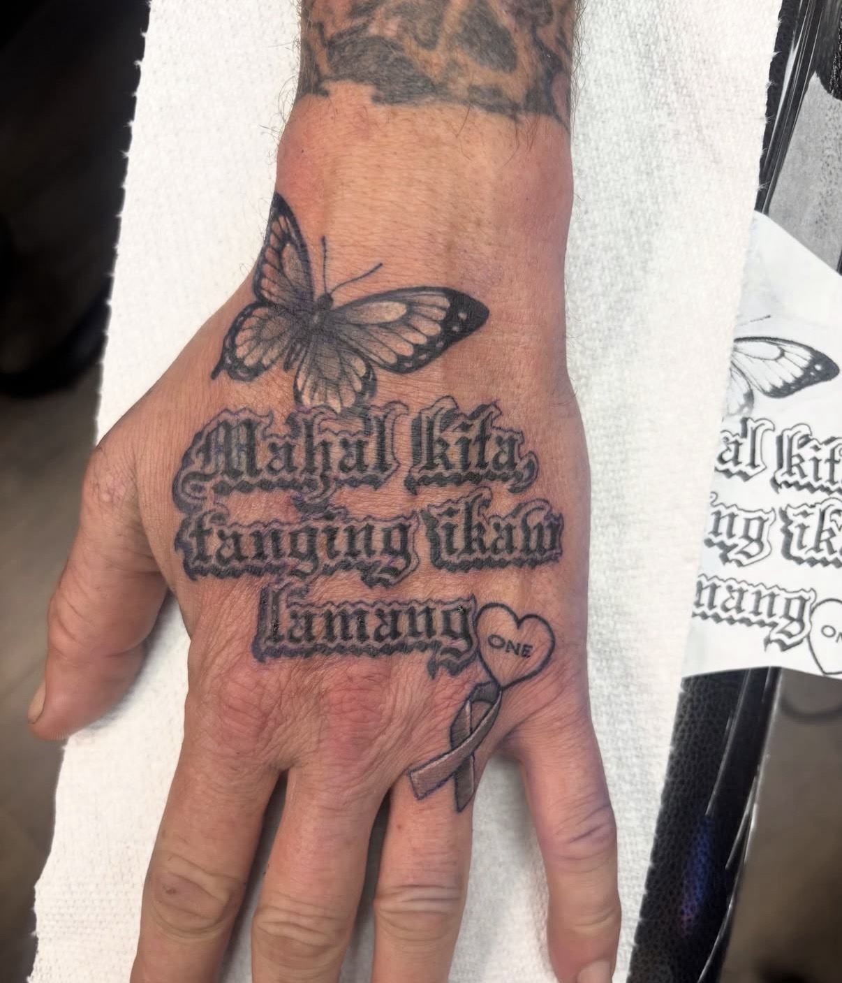 Butterfly and lettering hand tattoo